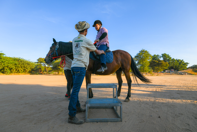 Du khách người Lào được hai nhân viên hỗ trợ trèo lên ngựa và chỉ cách nắm dây cương. Đây là thời điểm bắt đầu chuyến tham quan thành phố cổ Bagan.