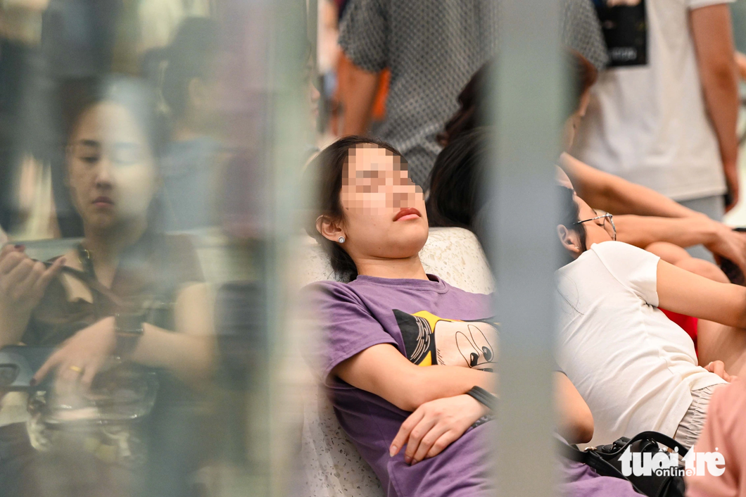 Nhiều người tỏ ra mệt mỏi, ngủ ngay tại ghế ngồi của trung tâm thương mại - Ảnh: HỒNG QUANG
