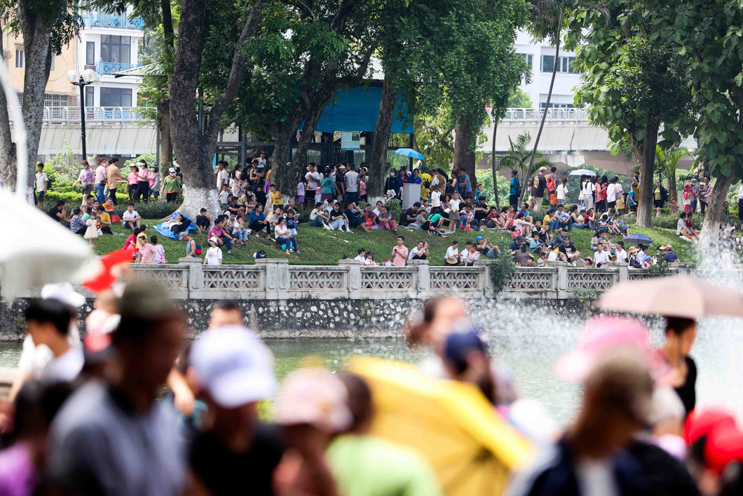 Thời tiết Hà Nội khá oi nóng, nhiệt độ gần trưa lên đến 37, 38 độ C, nhiều người phải ngồi trên thảm cỏ để tránh nóng - Ảnh: NGUYỄN KHÁNH